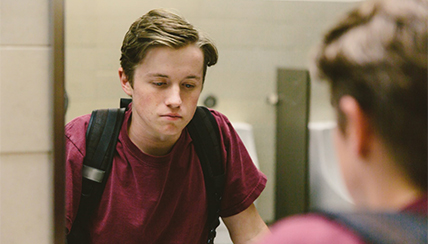 Stressed boy looking in a mirror in the bathroom